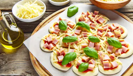 Cremede mini pizzastykker med skinke og smeltet ost